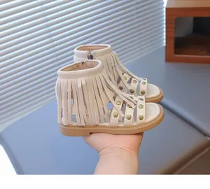 Détails des sandales gladiateurs crème avec pompons, rivets dorés et fermeture éclair