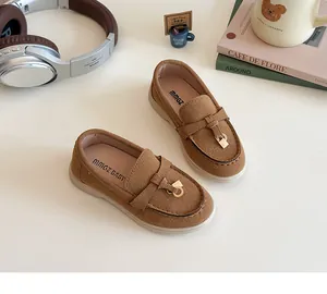 Detail of brown suede kids loafers with gold hardware and comfortable rubber soles