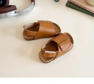 Detail of dark brown leather girl sandals with velcro strap and cork textured sole