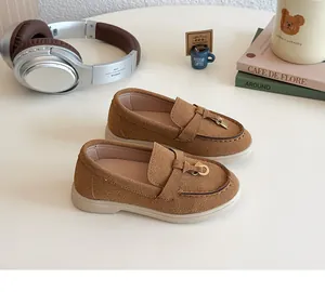 Detailed view of brown suede loafers for children with stylish metal buckles and non-slip soles