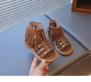 Détail de sandales gladiateur marron pour filles avec franges, clous dorés et fermeture