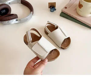 Detail view of white leather girls sandals with woven straps and adjustable velcro closure