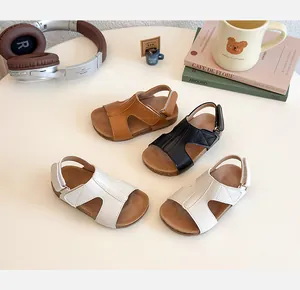 Flat lay of brown, black, and beige girls' sandals with velcro straps and cork soles