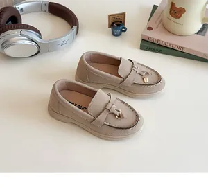 Detail of beige suede kids loafers featuring a golden lock charm in a cozy lifestyle setting