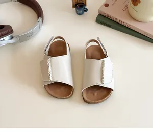Detail of girls' open-toe sandals featuring cream leather straps and velcro closures