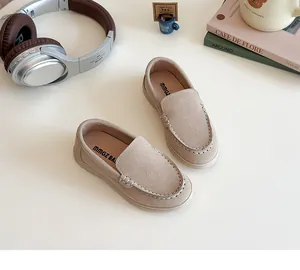 Dettaglio di mocassini scamosciati beige per bambini con cuciture bianche a contrasto