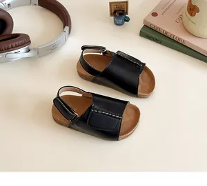 Detail of girls' black leather sandals with velcro straps and cork footbed in a lifestyle setting