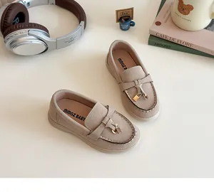 Detailed view of beige suede kids loafers with white stitching and gold lock charm accessory