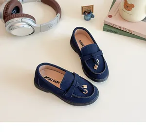 Detail of dark blue suede kids loafers with a gold lock charm and non-slip rubber soles