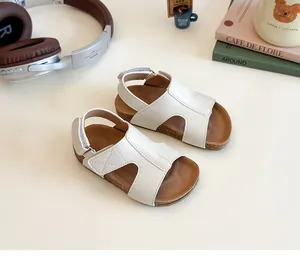 Detail view of white girls' sandals with velcro straps on a wooden table setup