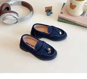 Detail of dark blue suede kids loafers with a gold padlock and bow on a clean surface