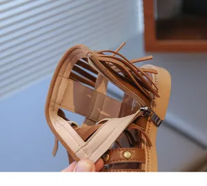 Détail de sandales à franges marron en suède avec fermeture éclair et rivets rétro