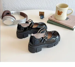 Details glänzender Lackleder-Mary-Janes mit Doppelriemen auf einem Schreibtisch