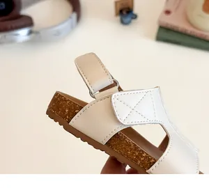 Detail of girls' white sandals showing velcro straps and cork texture midsole