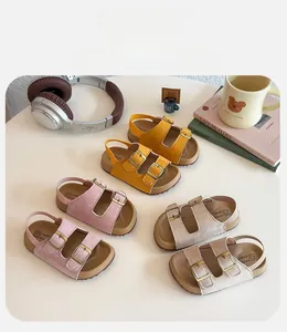 Trois paires de sandales à double boucle pour enfants sur une table blanche