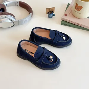 Navy blue suede kids loafers with a bow and gold buckle on a white tabletop
