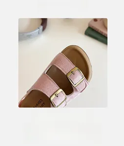 Détail de sandales enfant en daim rose avec boucles métalliques et bout rond souple