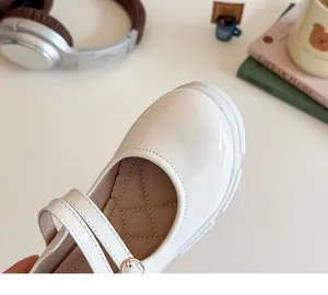 Detail von weißen Mary Jane Schuhen aus Lackleder mit Metallschnalle und dicken Sohlen