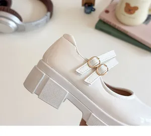 Detailansicht der weißen Lackleder-Mary Janes mit doppelten goldenen Schnallen und Plateau