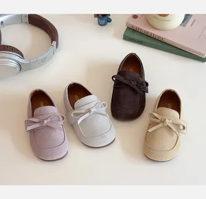 Flat lay of girl's bow loafers in pink, beige, and brown with soft suede texture