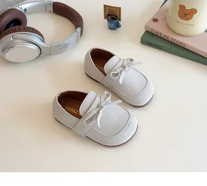 Top view of beige children's bow flat shoes with soft suede texture and round toe