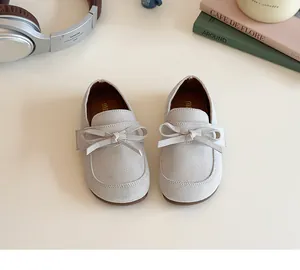 Detail shot of light grey suede children's loafers with a matching bow and leather lining