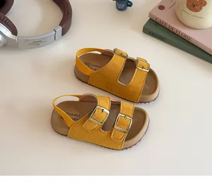 Gros plan de sandales jaune vif pour tout-petits avec doubles boucles sur fond crème