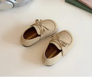 Close-up of beige faux suede toddler flats featuring a soft bow and branded inner sole