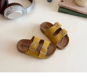 Detailed view of yellow faux suede children's sandals with double metal buckles and cork sole