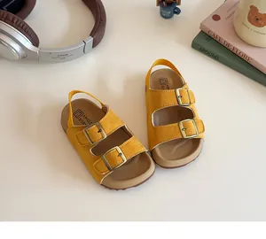 Vue détaillée des sandales en daim jaune pour bambins avec boucles sur un bureau cosy