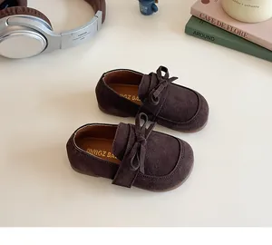 Close-up of dark brown suede kids princess shoes with bow detail and retro vibe