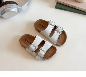 Close-up of kids cork slide sandals with off-white suede straps and silver buckles
