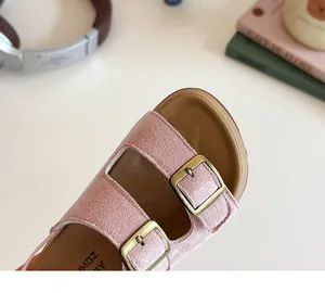 Gros plan sur des sandales roses en daim pour enfants avec doubles boucles dorées
