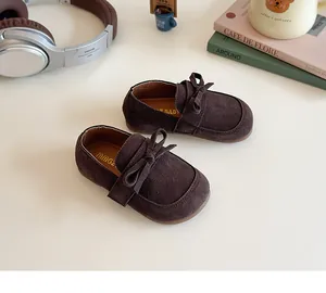 Close-up of children's dark brown suede shoes with elegant bow and interior gold logo