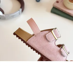 Détail de sandales roses en daim pour enfants avec boucles cuivrées et semelle épaisse