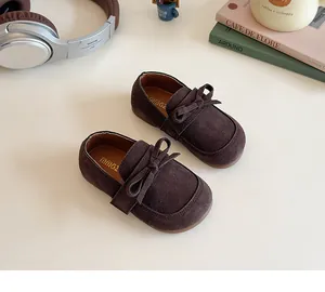 Detailed view of kids vintage brown suede loafers featuring a bow and round toe design