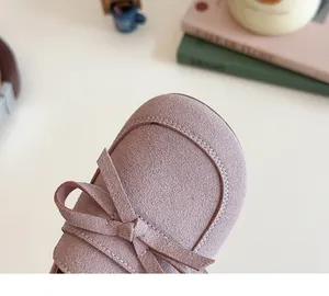 Detail view of the soft mauve suede texture and delicate bow on children girls shoes
