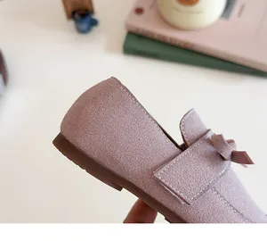 Detail of soft suede kids flats in dusty pink with a delicate bow and non-slip sole