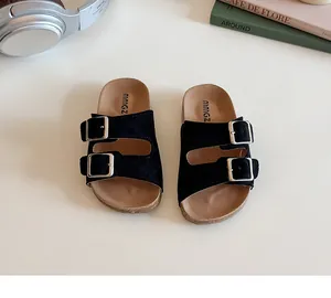Detail of children's black double-buckle sandals featuring suede straps and cork footbed