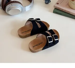Detail of children's black suede slide sandals with double buckles and cork footbed