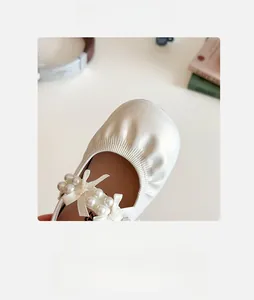 Détail de chaussures filles beige crème avec perles élégantes et nœud en soie