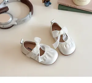 Close-up of cream Mary Jane shoes with large organza bow and elastic frill detail