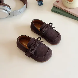 Brown suede loafers for girls with bow tie design in a cozy minimalist setting