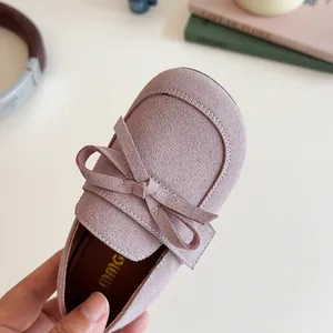 Pink suede girls Mary Jane shoes with bow decoration shown in a lifestyle setting