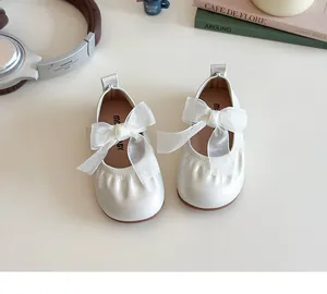 Close-up of pearl white girls flats with oversized organza bow and elasticated round toe