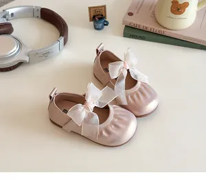 Detailed top view of pink satin Mary Jane shoes with mesh bow for girls on creamy background