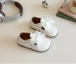 Detailed view of white Mary Jane girl shoes with lace bow and woven texture surface