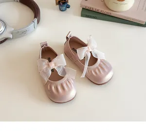 Detail of girls' pearlescent pink shoes featuring a mesh bow and elastic strap design