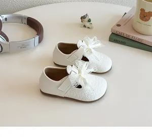 Detail of girls beige Mary Jane shoes with lace bow and woven texture on the upper