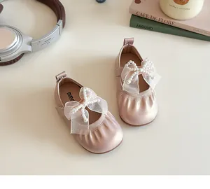 Close-up of pink Mary Jane shoes with mesh bow and pearls for girls on a table